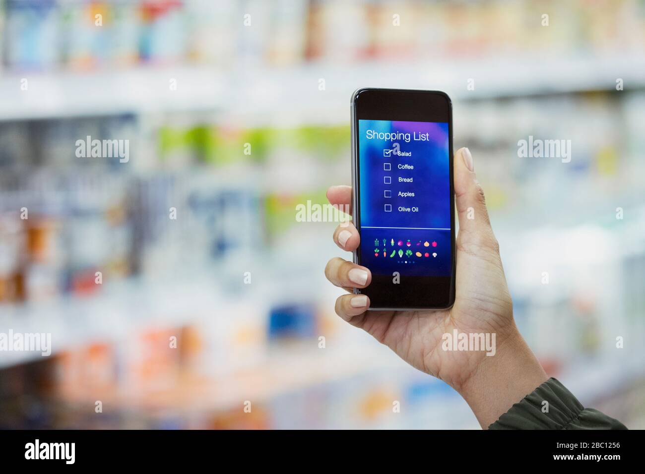 Persönliche Perspektive Frau überprüft digitale Einkaufsliste auf Smartphone im Supermarkt Stockfoto