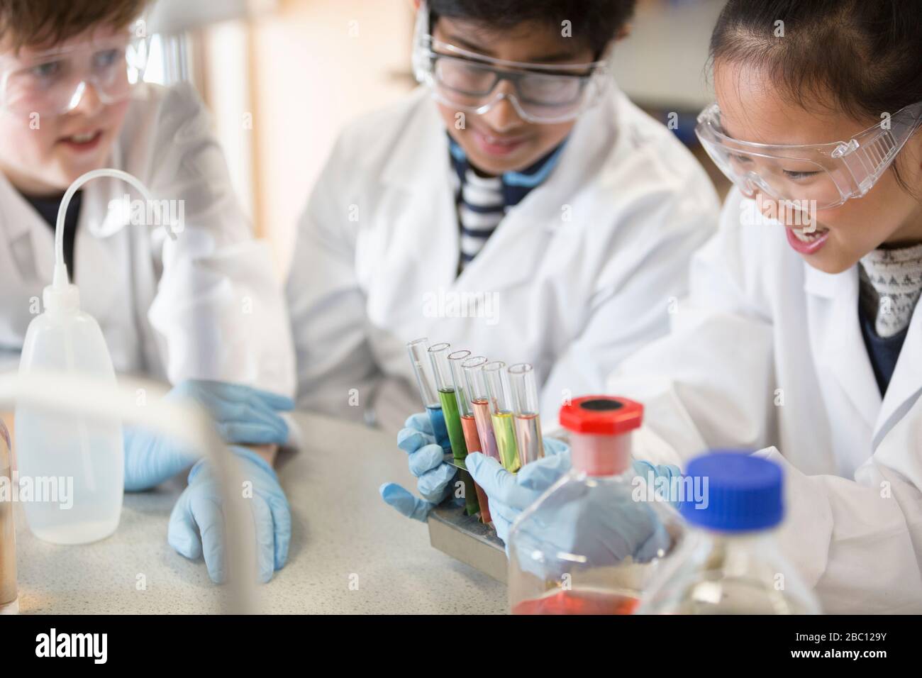 Studenten, die Flüssigkeiten im Reagenzglasgestell untersuchen und wissenschaftliche Experimente im Laborraum durchführen Stockfoto