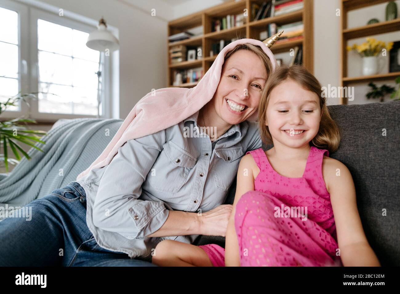 Porträt der glücklichen Mutter und ihre kleine Tochter sitzen zusammen auf der Couch Spaß Stockfoto