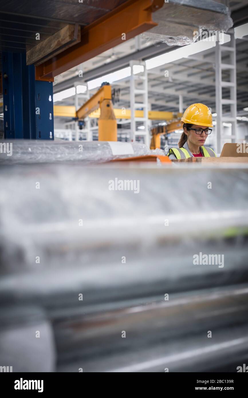 Fokussierte Arbeiterinnen verwenden Laptop in Stahlfabrik Stockfoto