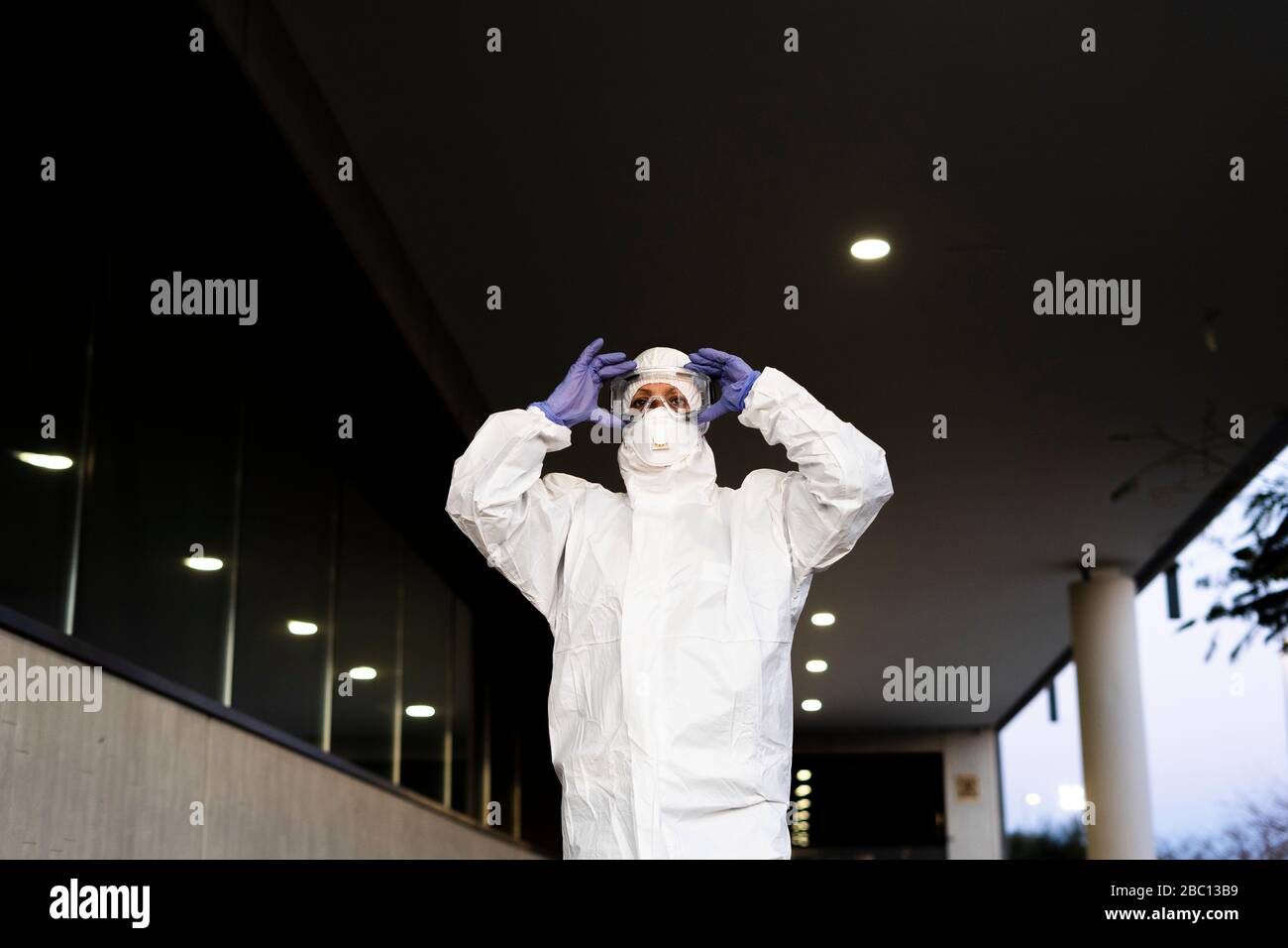 Wissenschaftlerin mit Schutzanzug und Maske und Schutzbrille Stockfoto