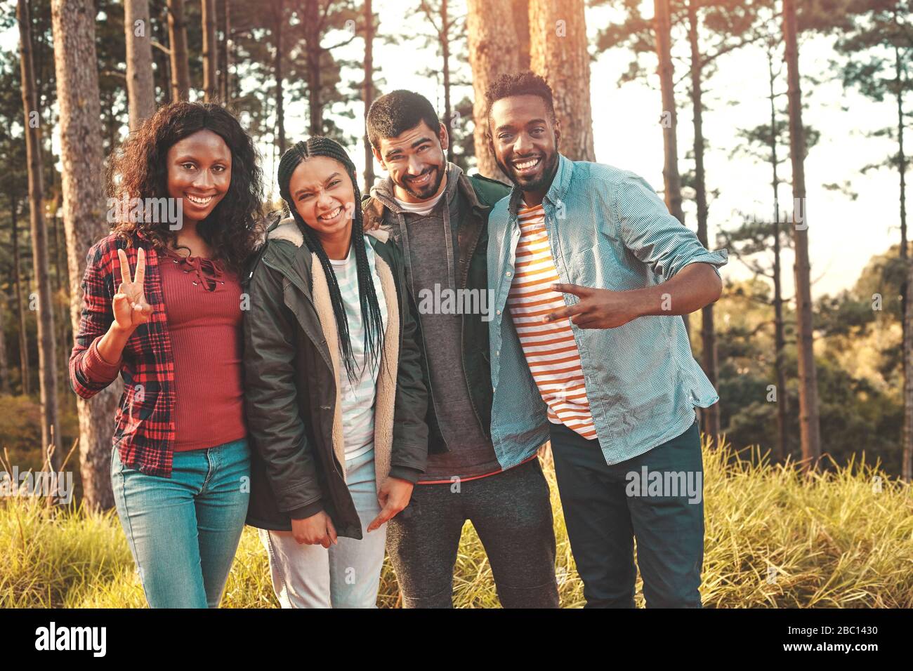 Portrait selbstbewusste junge Freunde, die ein Friedenszeichen in Wald gestikulieren Stockfoto