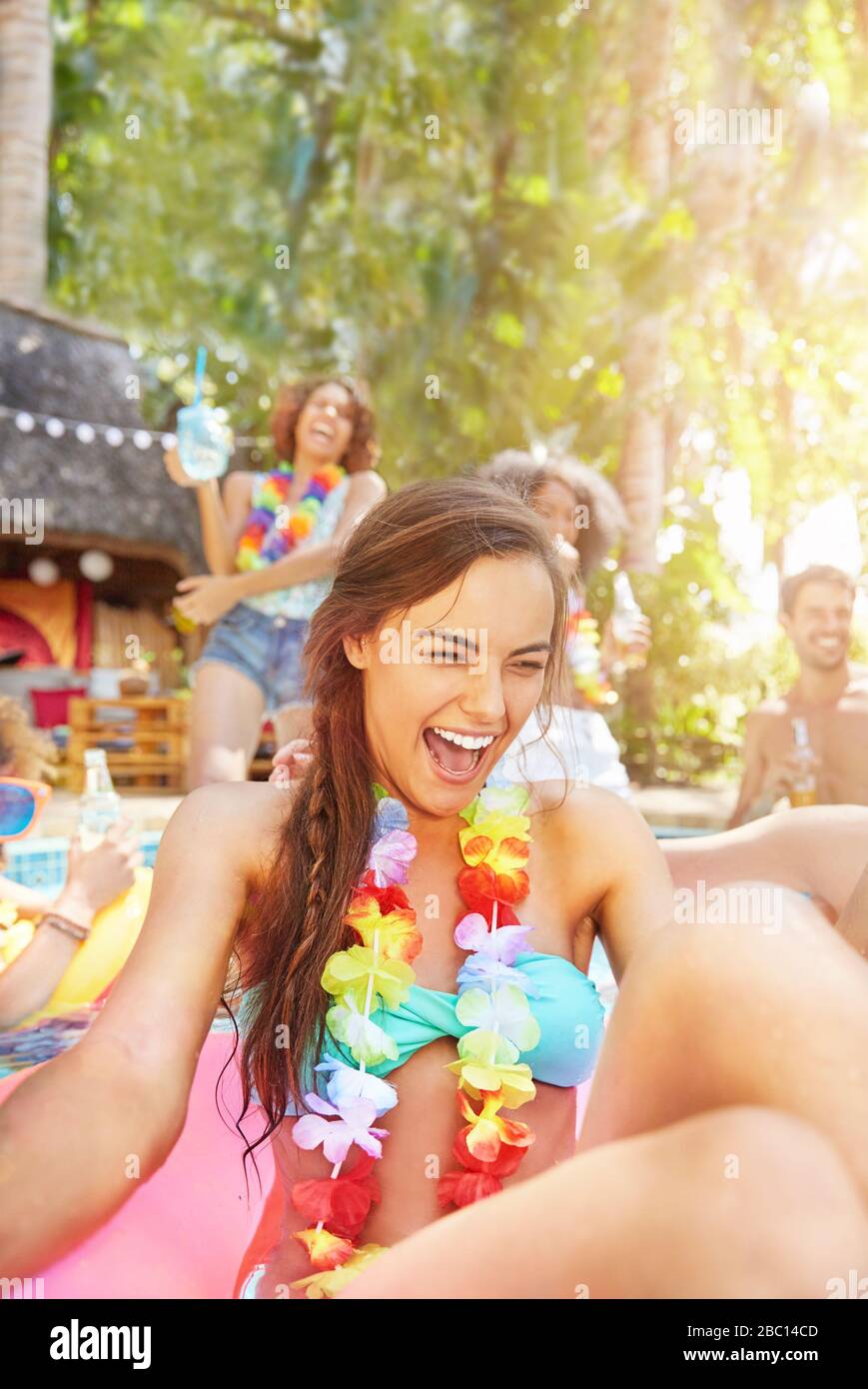 Begeisterte, lachende junge Frau, die im Sommer-Schwimmbad Lei trägt Stockfoto