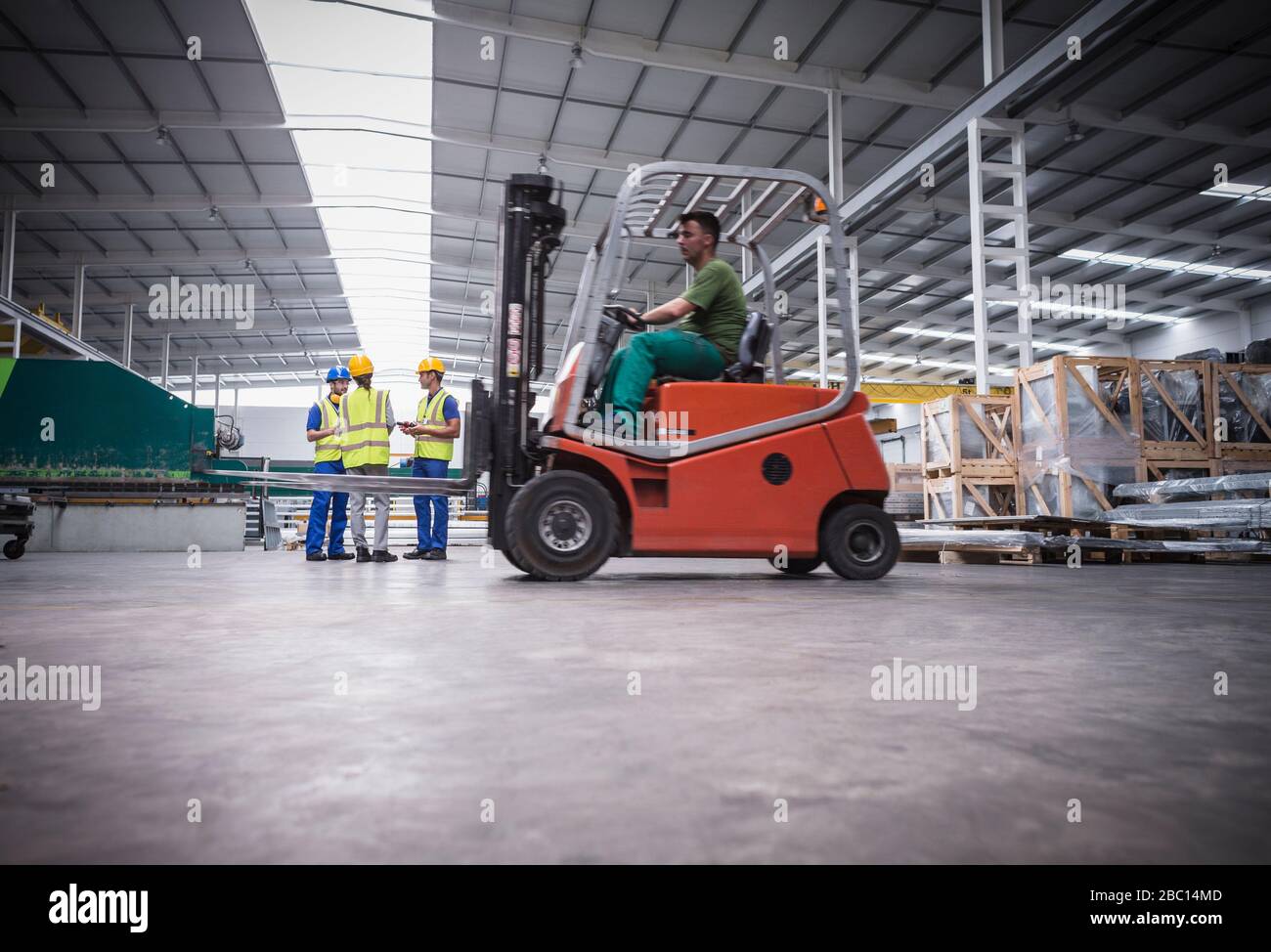 Arbeiter, die im Werk mit Gabelstapler fahren Stockfoto