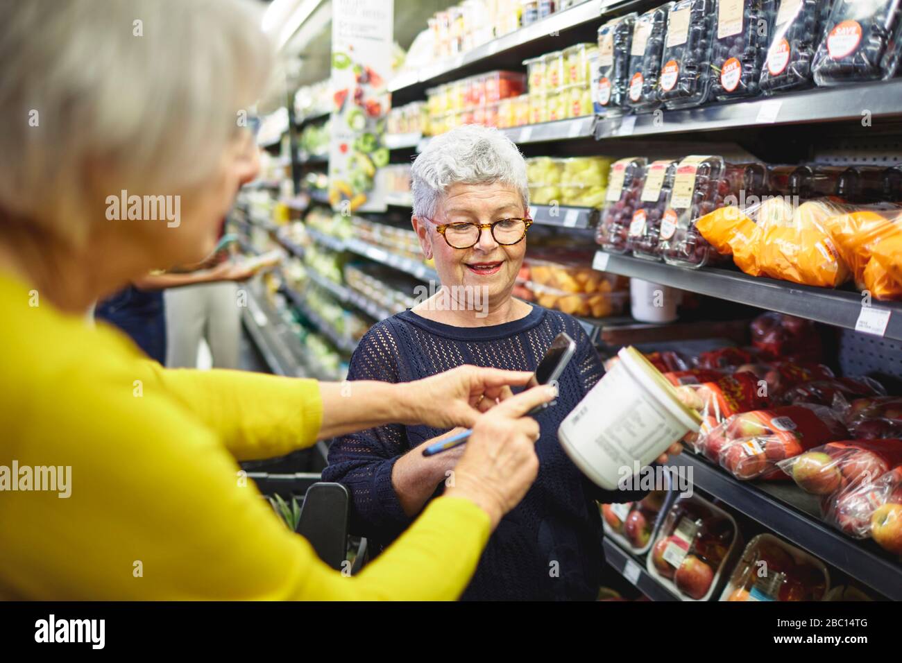 Seniorinnen mit Smart-Phone-Lebensmittelgeschäft im Supermarkt Stockfoto