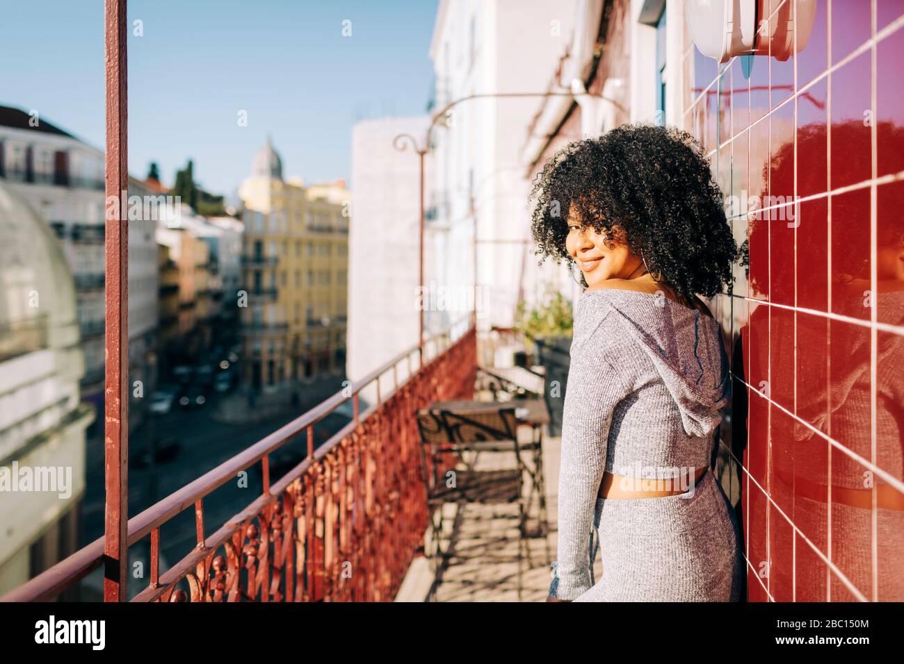 Portrait der jungen Frau mit lockigen Haaren auf dem Balkon Stockfoto