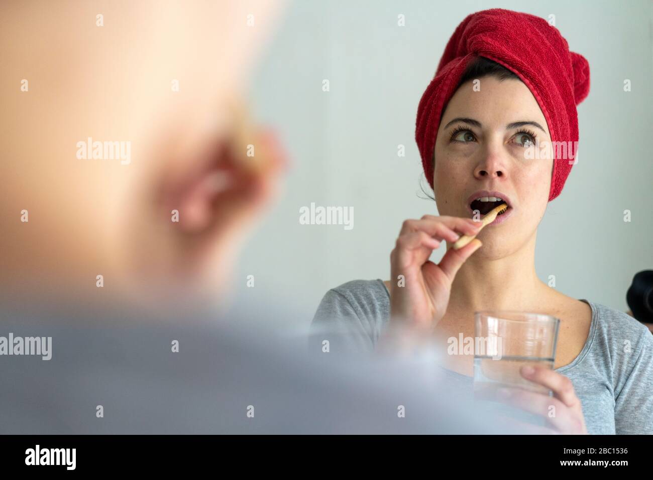 Porträt einer Frau mit Kopf in einem Handtuch gewickelt putzt heitere Zähne mit Holzzahnbürste Stockfoto
