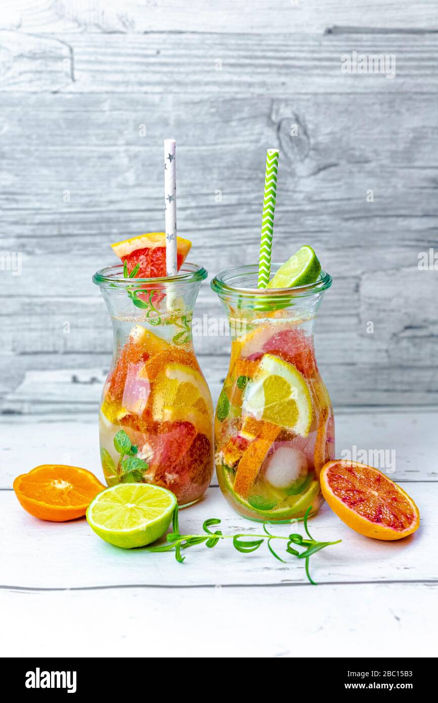 Gläser mit Wasser mit verschiedenen Zitrusfrüchten, Minze und Rosmarin Stockfoto