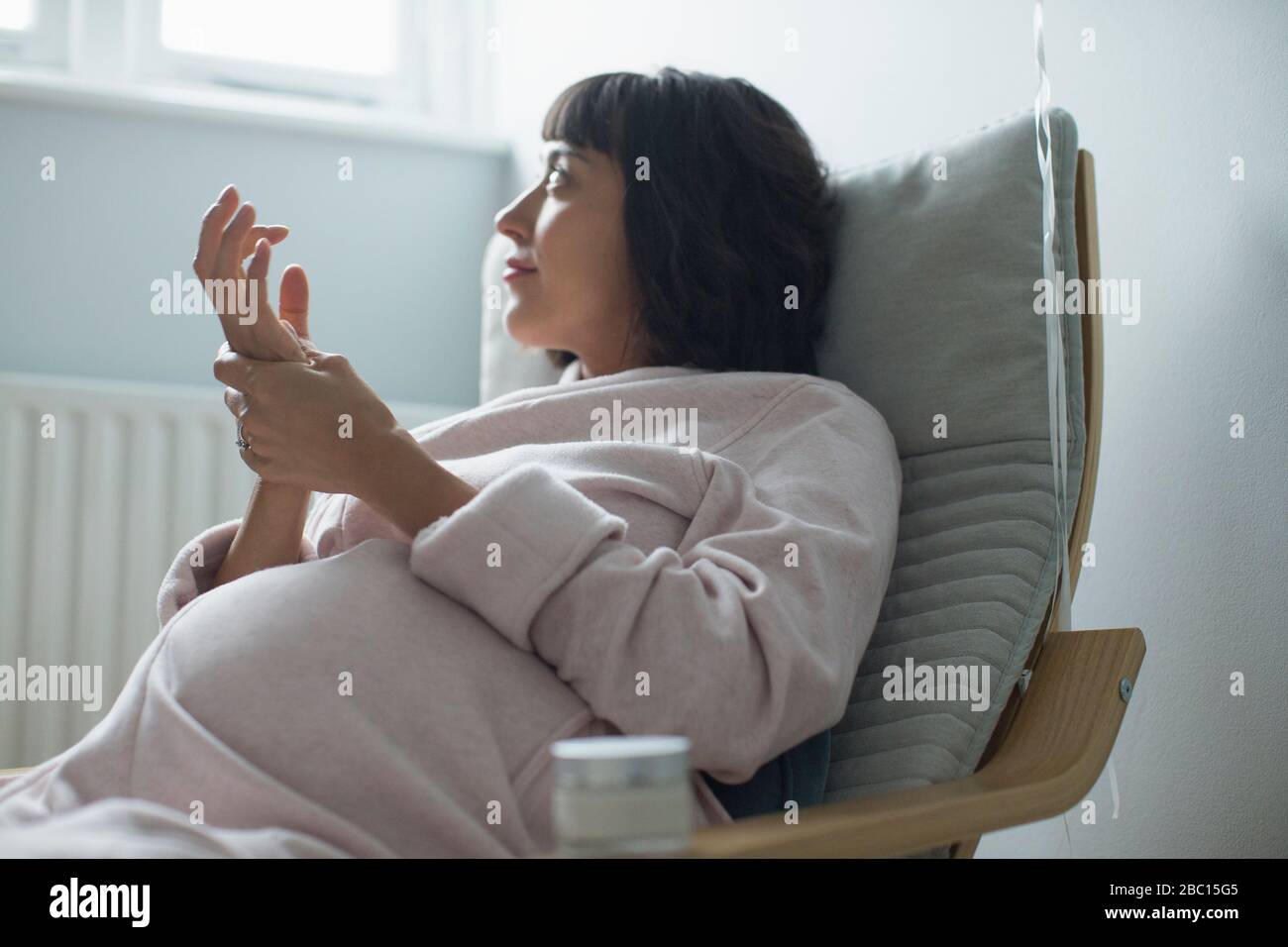 Schwangere Frau im bademantel reibt die Hände Stockfoto