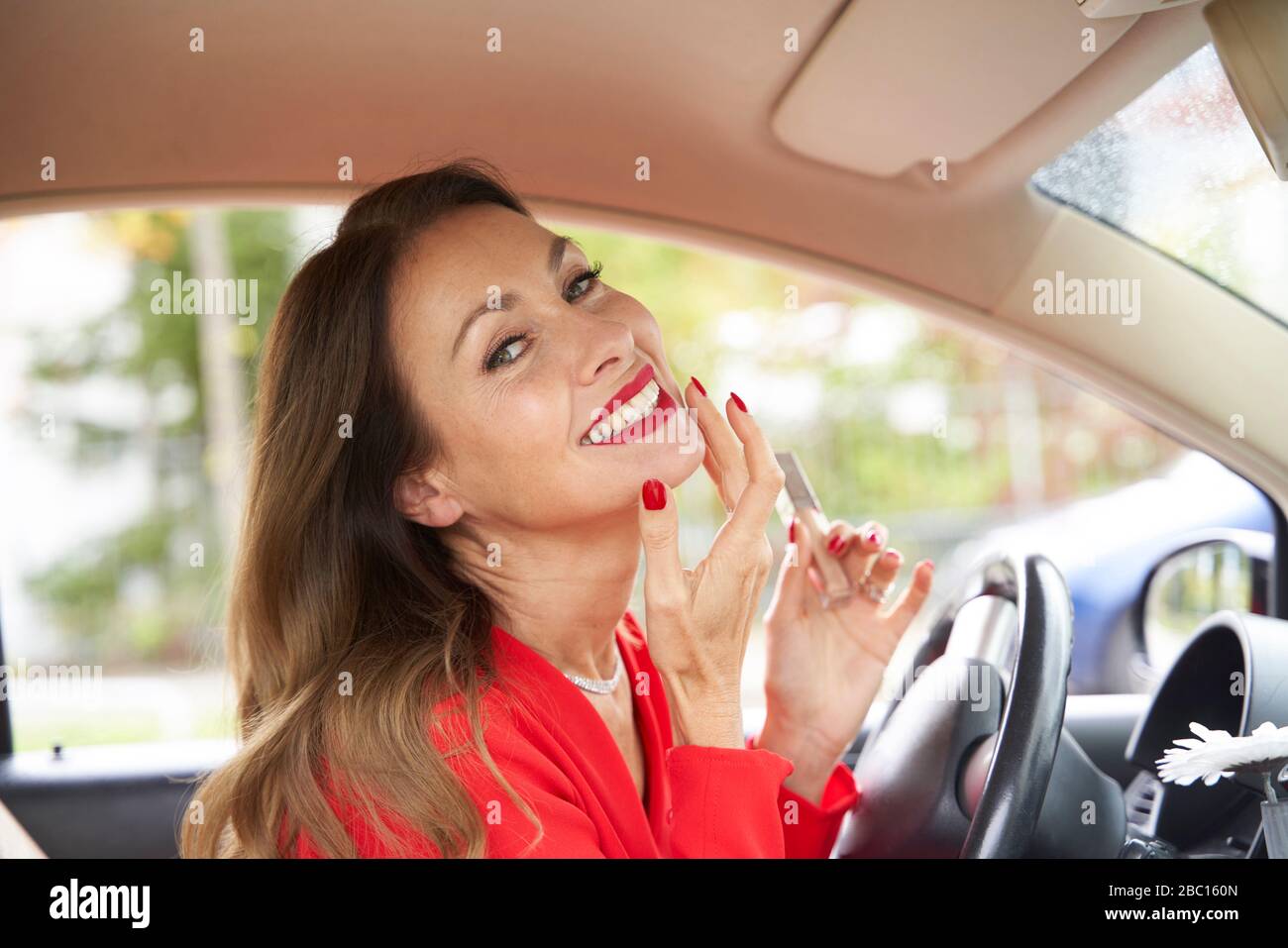 Porträt von glücklichen reifen Frau mit roten Lippen und Nägel im Auto Stockfoto