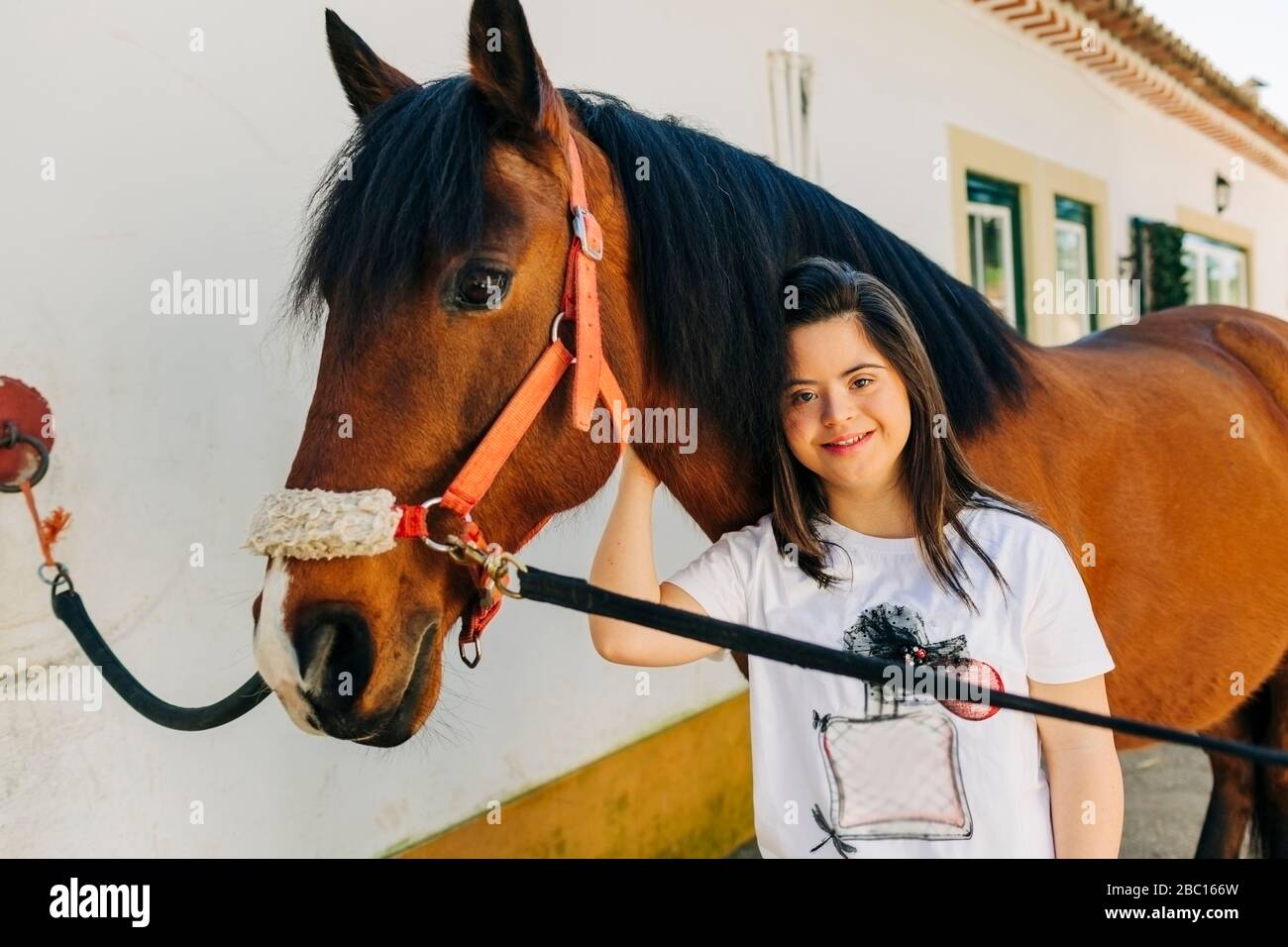 Teenager mit Down-Syndrom kümmert sich um Pferd und Vorbereitung Pferd zu reiten Stockfoto