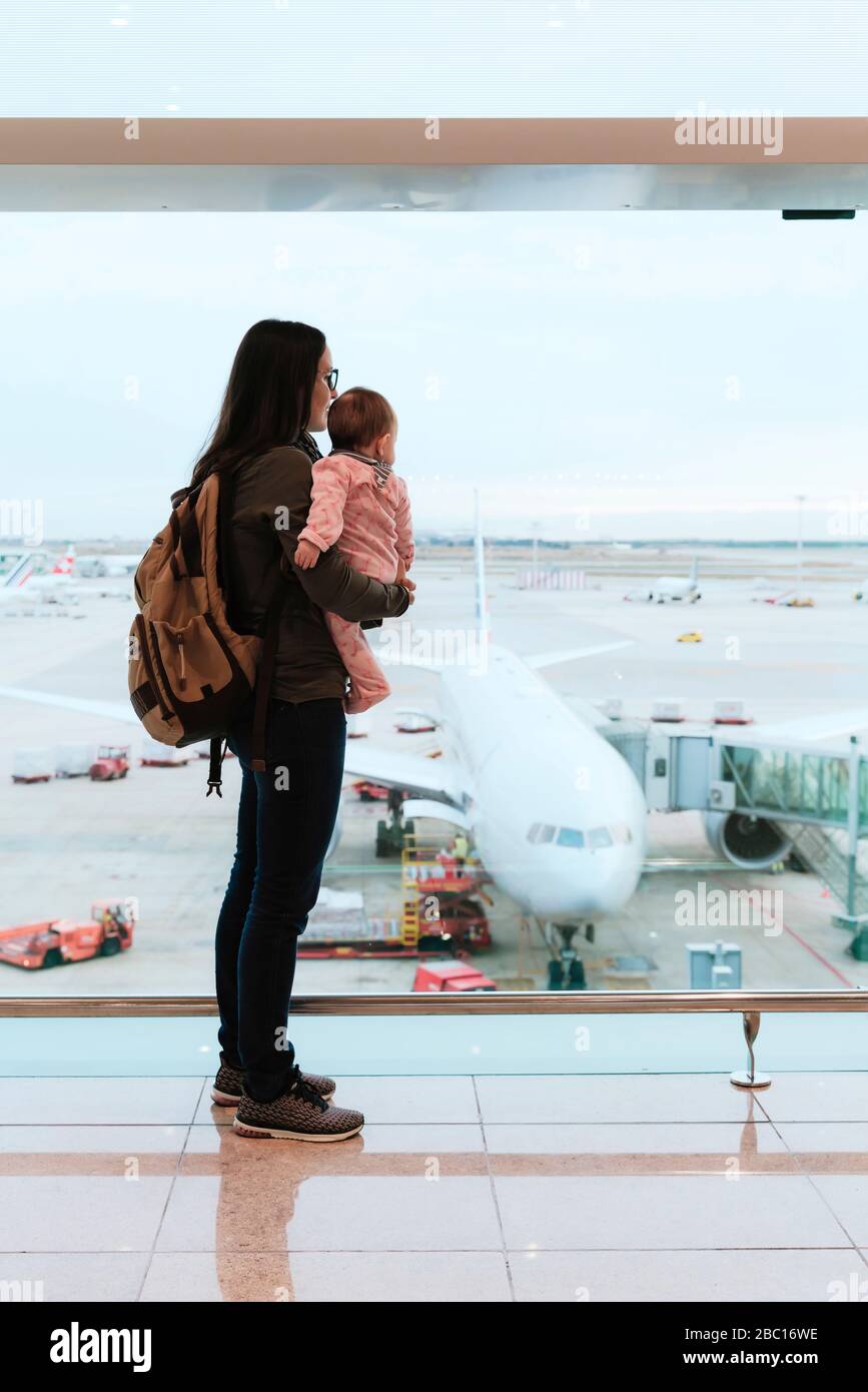 Mutter mit Baby und Rucksack am Flughafen vor einem Flugzeug am Flughafen in Barcelona, Spanien Stockfoto