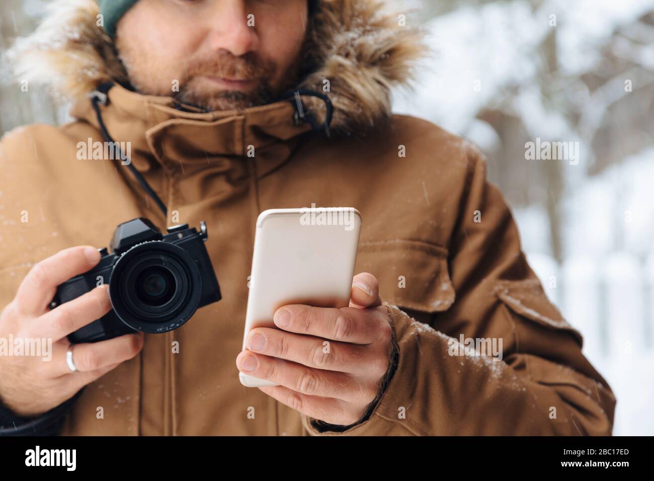 Crop Ansicht des Menschen mit Digitalkamera Blick auf Handy im Winter Stockfoto
