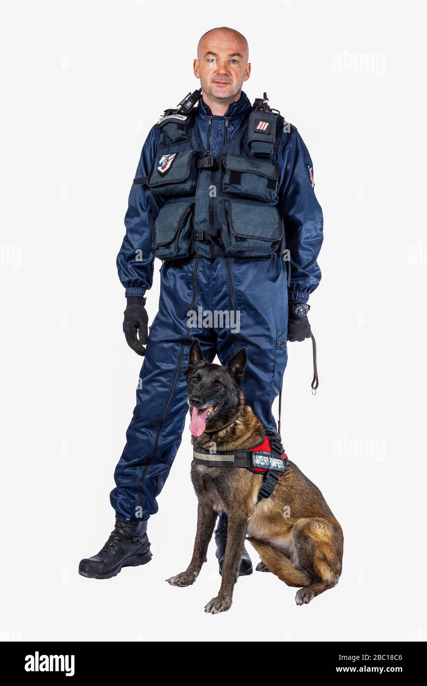 HUNDEFÜHRER DER FEUERWEHR UND SEIN HUND, MALINOIS ODER BELGISCHER HIRTE, SUCHEN UNIFORM, DIE BEI DER SUCHE NACH VERLORENEN PERSONEN GETRAGEN WIRD Stockfoto