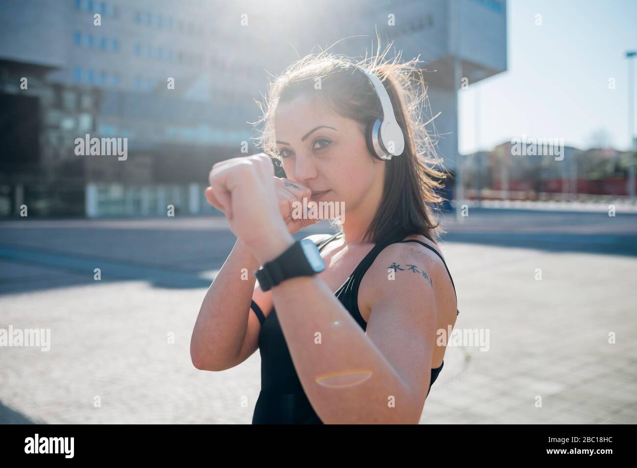 Porträt einer selbstbewussten sportlichen jungen Frau mit Kopfhörern in der Stadt Stockfoto