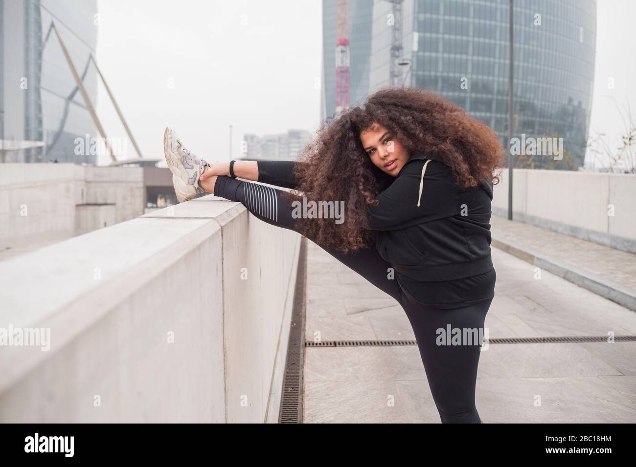 Plus Größe sportliche junge Frau Stretching in der Stadt Stockfoto