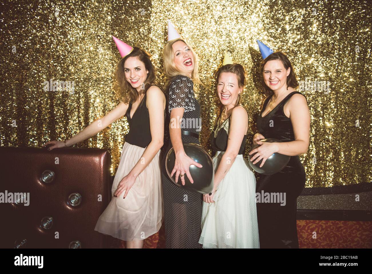 Porträt von vier glücklichen Frauen, die in einem Club Partyhüte tragen Stockfoto