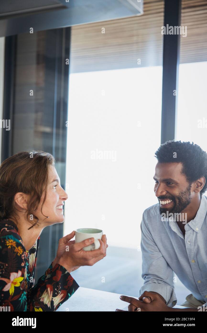 Multiethnisches Paar trinkt Kaffee und spricht Stockfoto
