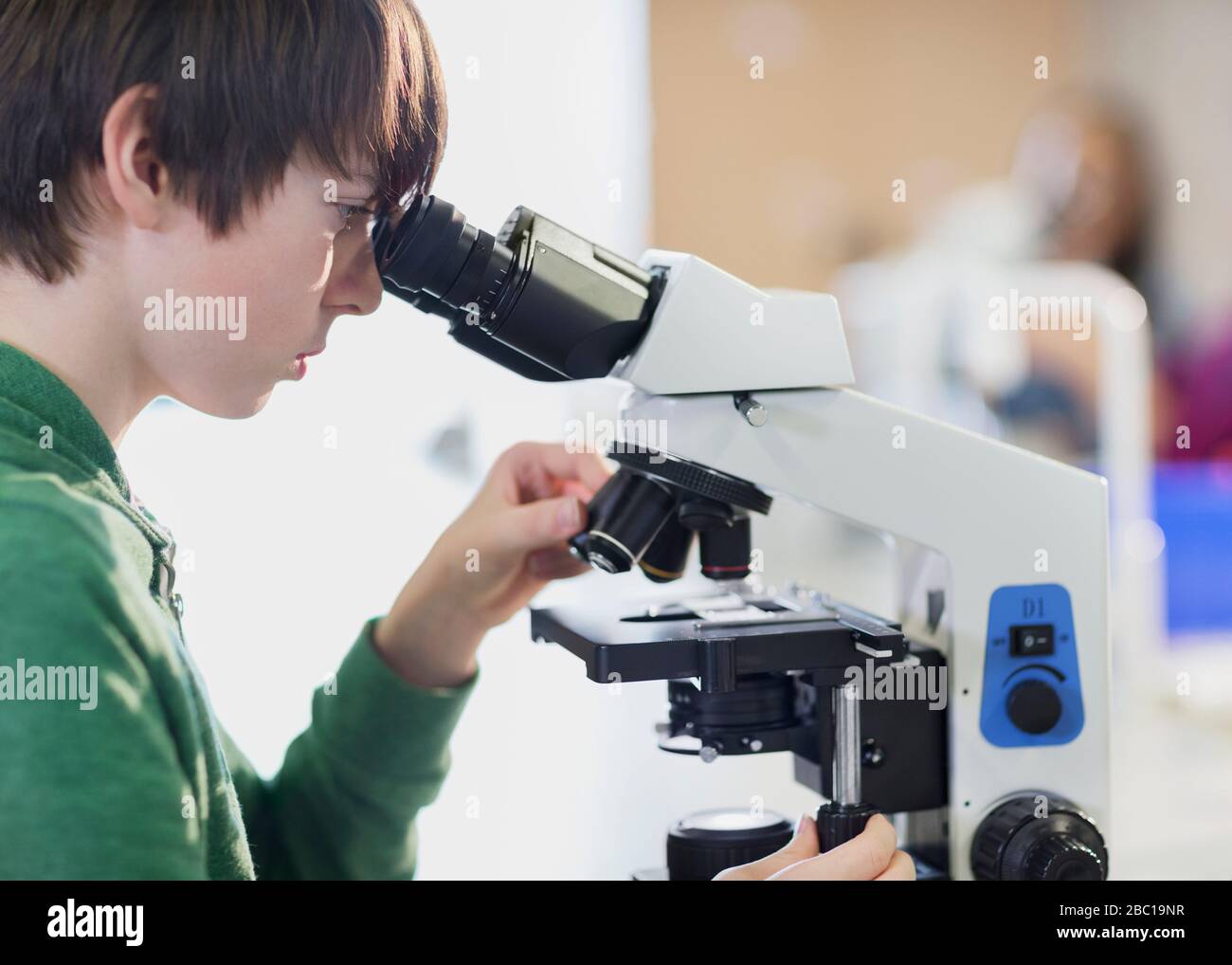 Schüler mit Fokus und Mikroskop im Klassenzimmer Stockfoto