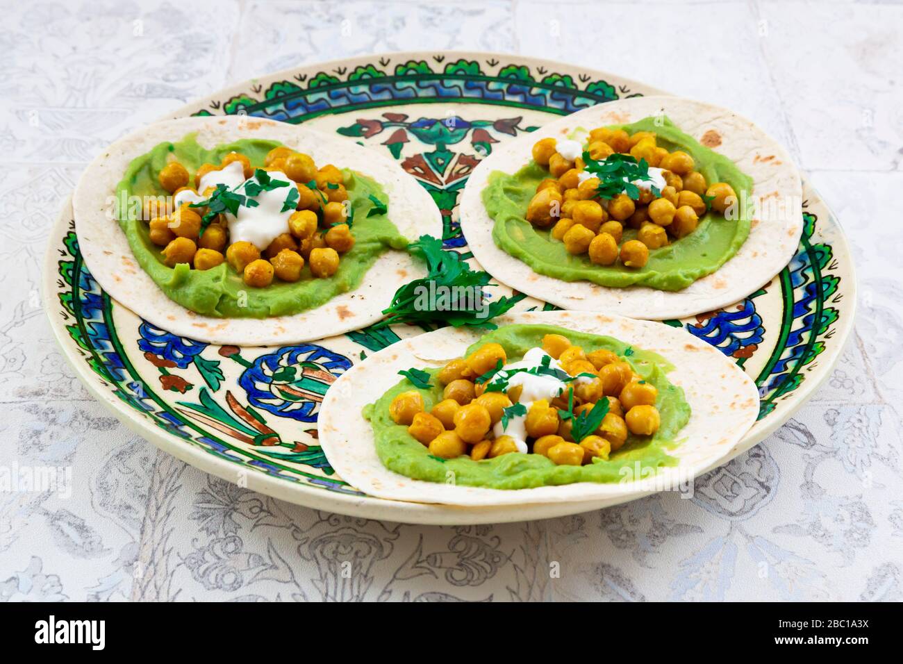 Pita-Brote mit Avocados, Kurkuma-Kichererbsen, Joghurt und Petersilie Stockfoto