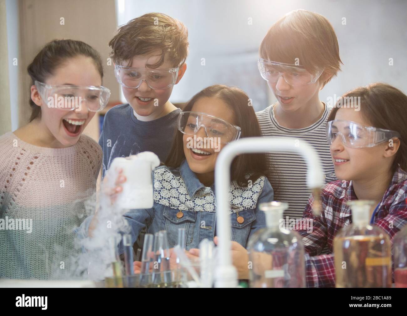 Überraschte Studenten, die wissenschaftliche Experimente durchführen und dabei chemische Reaktionen im Klassenraum-Labor beobachten Stockfoto