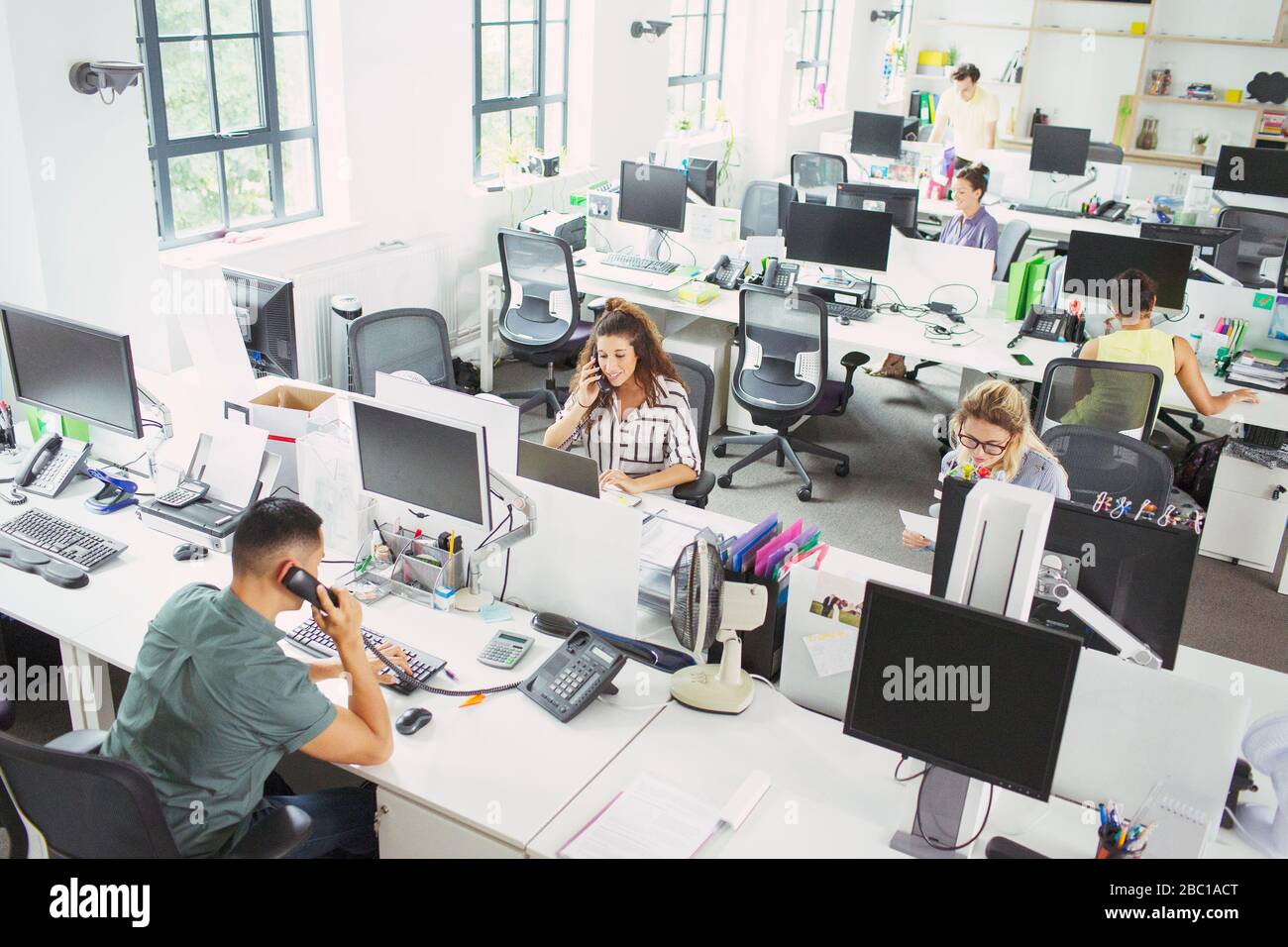 Geschäftsleute, die an Schreibtischen im Büro mit offenem Schnitt arbeiten Stockfoto