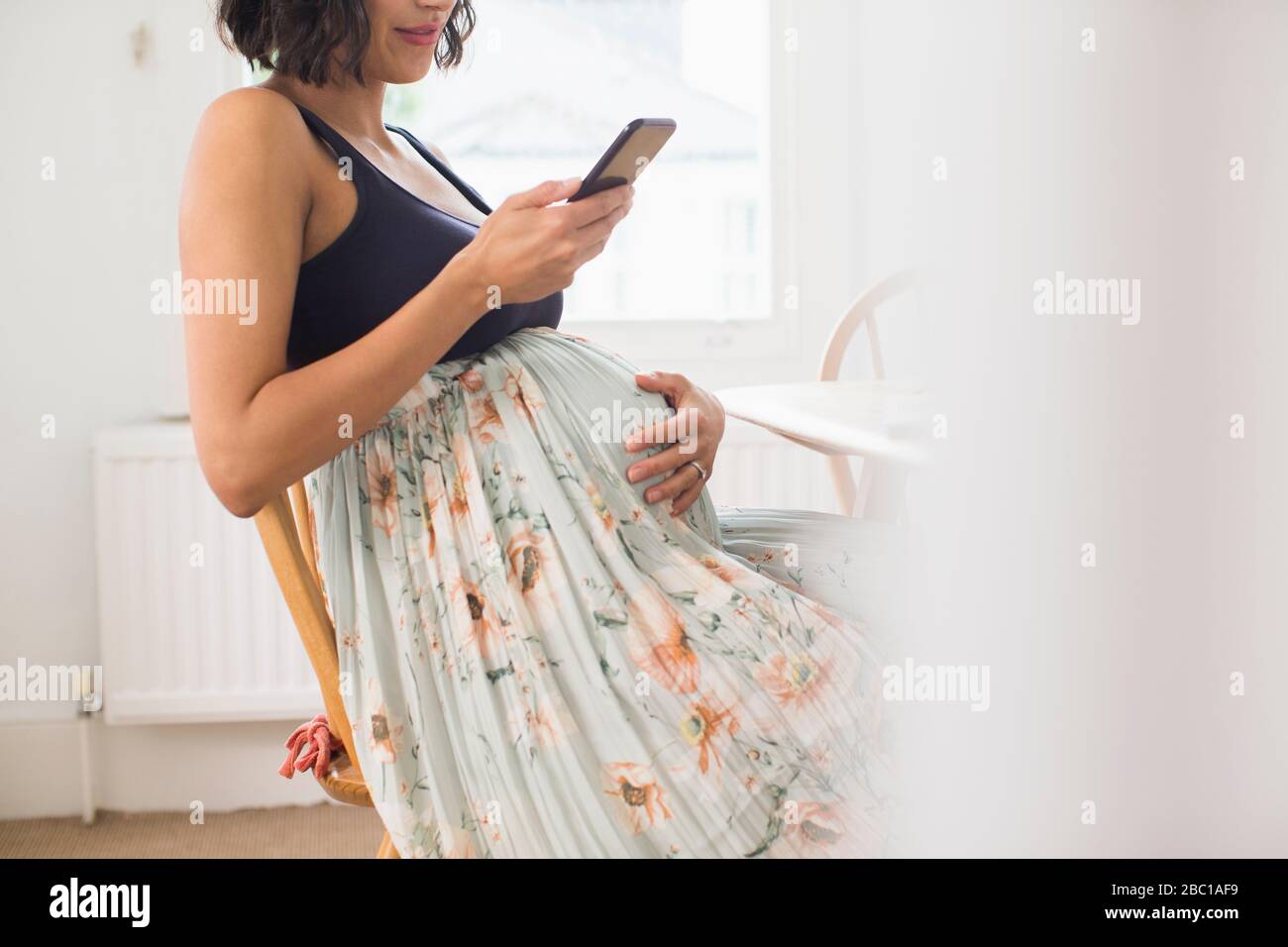 Schwangere Frau im Blumenrock mit Magen Stockfoto