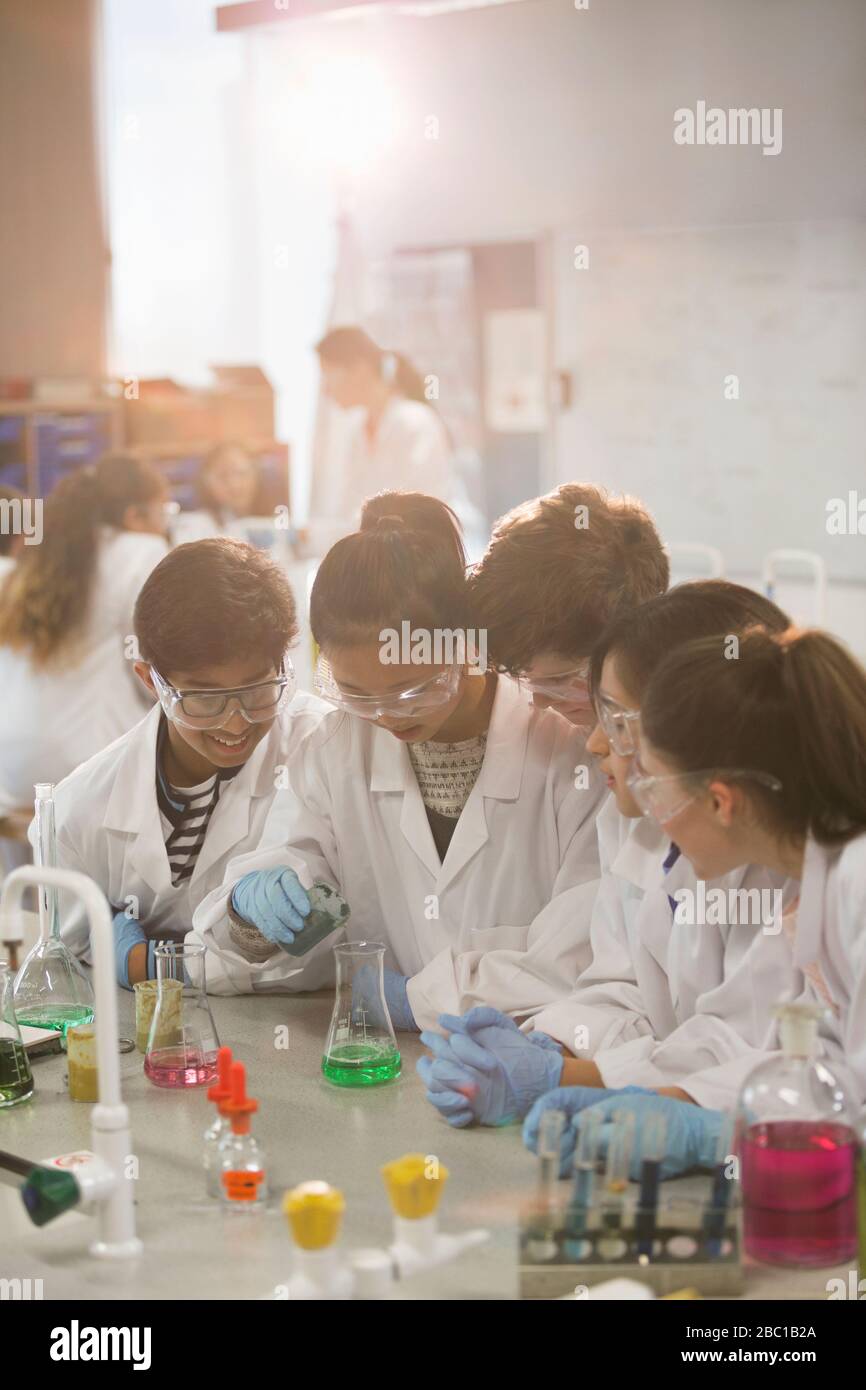 Studenten, die wissenschaftliches Experiment durchführen und Flüssigkeit im Becher in Laborräumen gießen Stockfoto