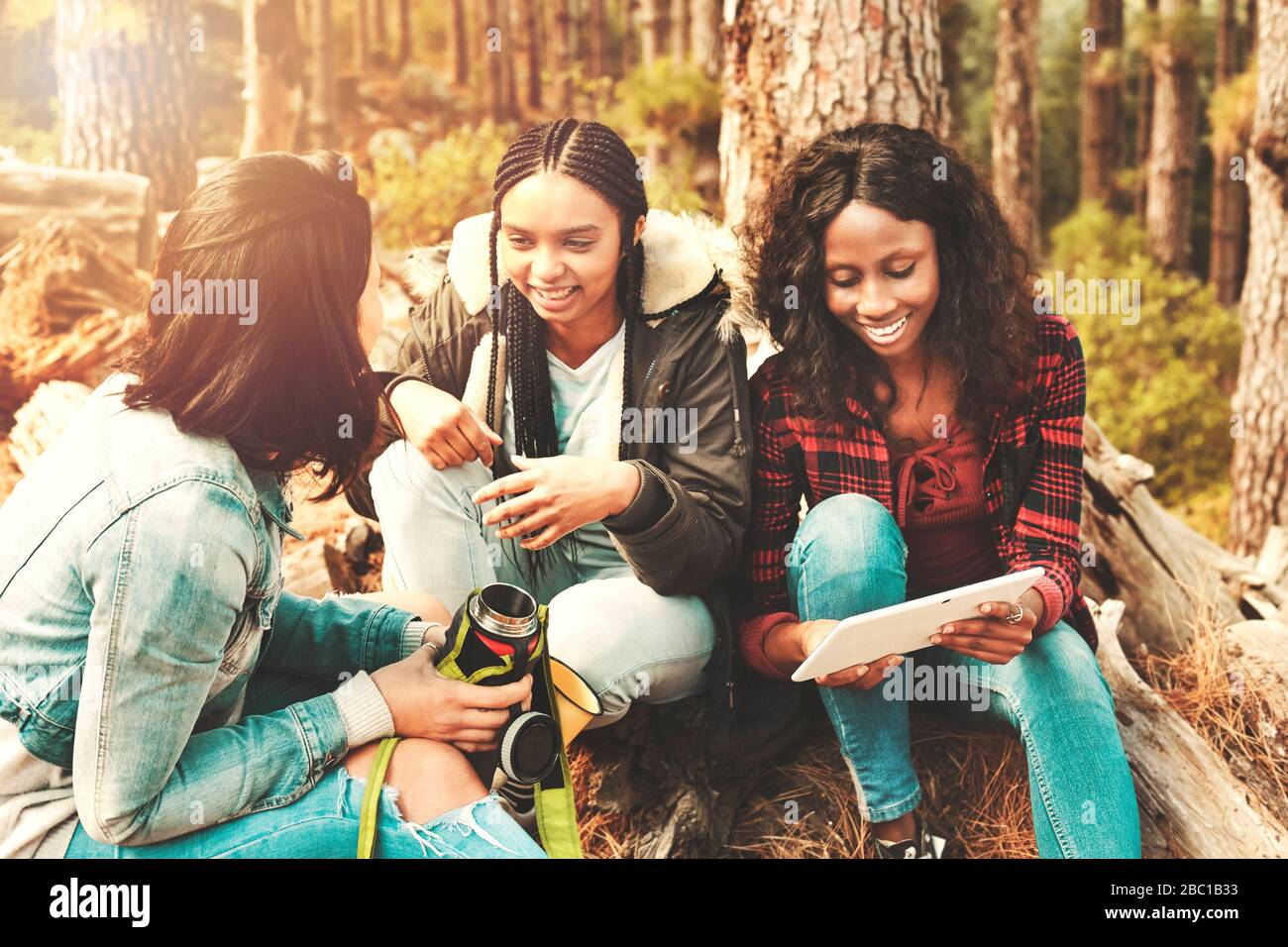 Junge Frauen trinken Kaffee und verwenden digitale Tabletts im Wald Stockfoto
