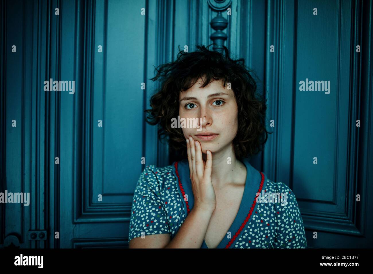 Porträt einer jungen Frau vor der blauen Holztür Stockfoto