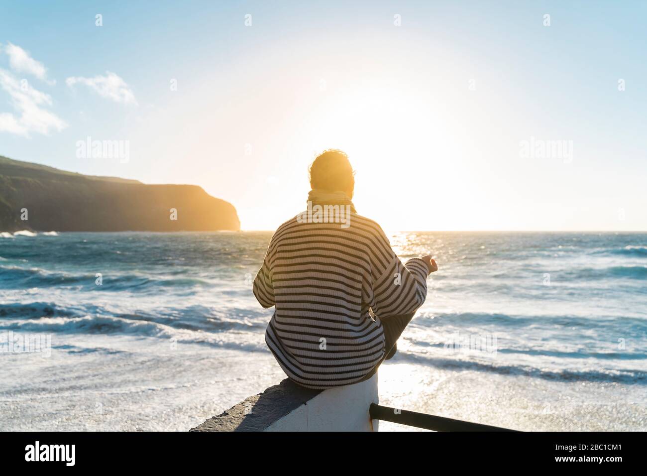 Mann meditiert an der Küste bei Sonnenuntergang, Sao Miguel Insel, Azoren, Portugal Stockfoto