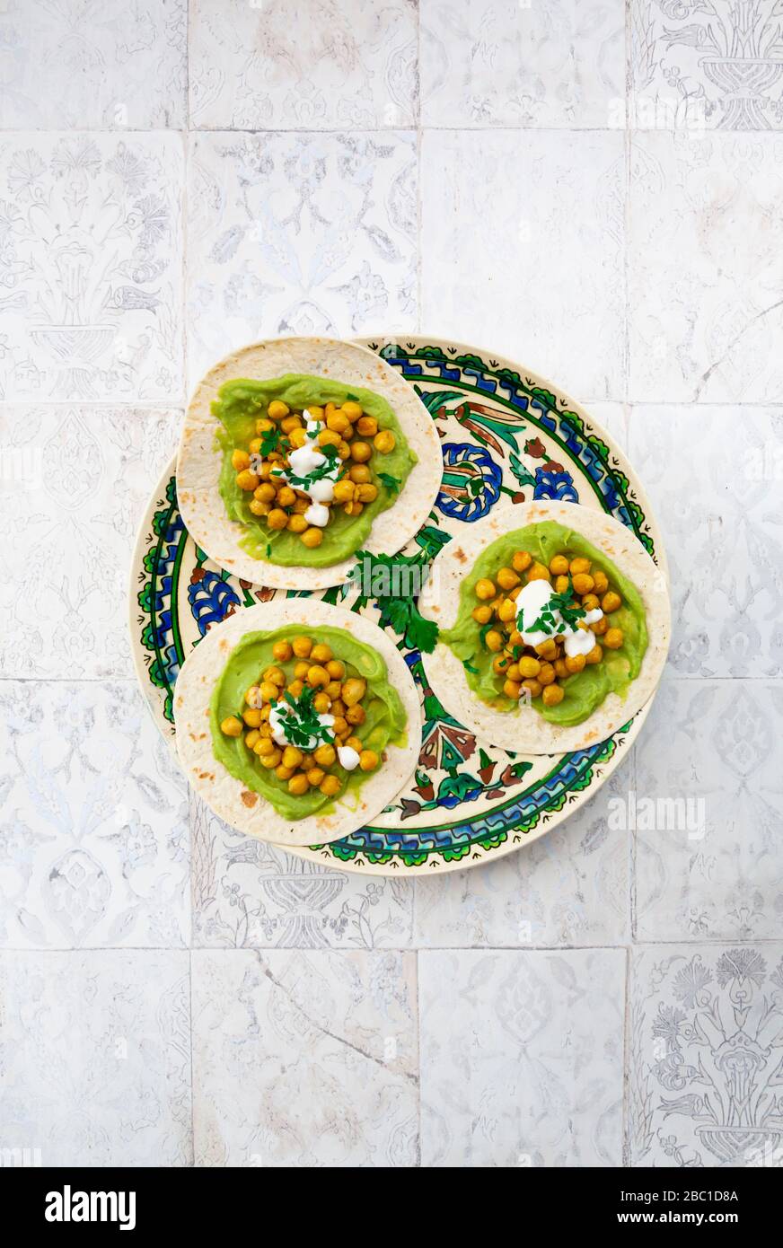 Pita-Brote mit Avocados, Kurkuma-Kichererbsen, Joghurt und Petersilie Stockfoto