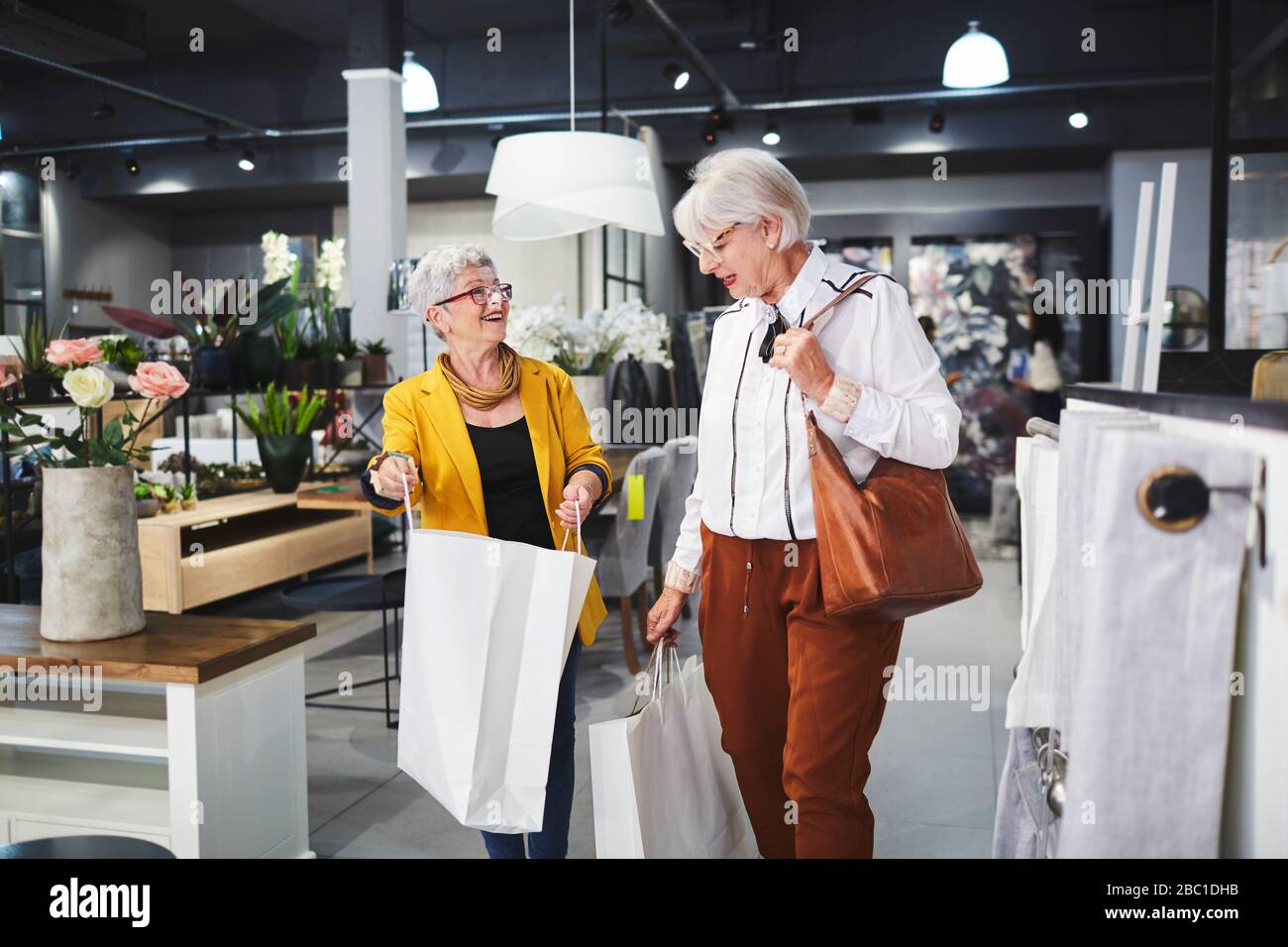 Seniorinnen Freunde verlassen Hauswarenladen mit Einkaufstaschen Stockfoto