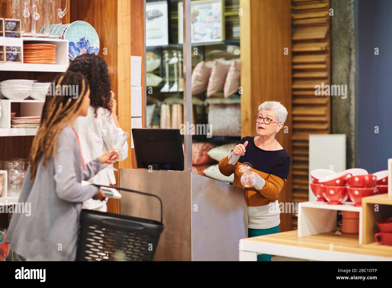 Leitende Kassiererin hilft Frauen beim Einkaufen im Warenhaus Stockfoto
