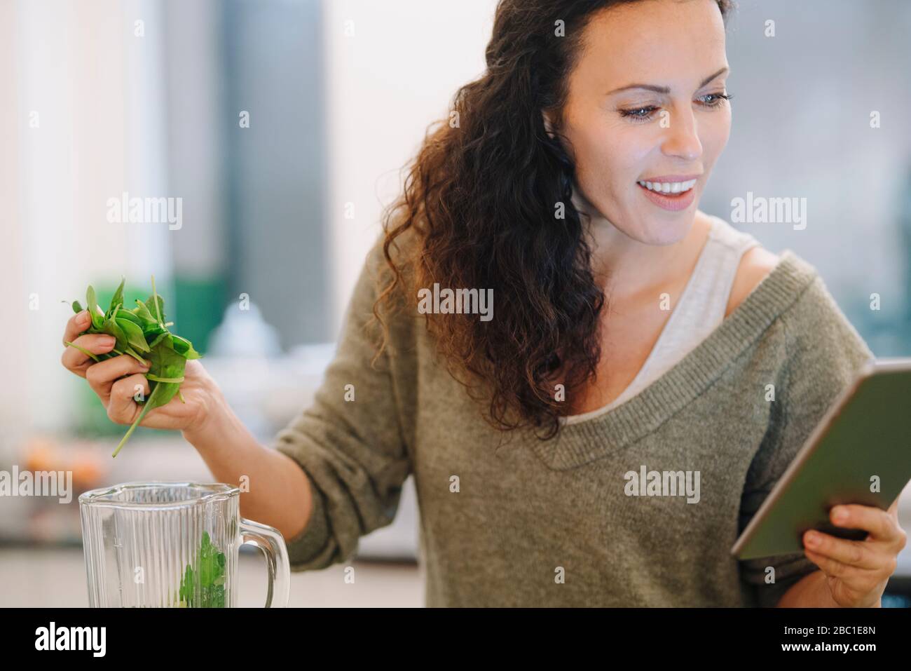 Fit Frau steht in der Küche, die Zubereitung von gesunden Smoothie, mit Online-Rezept Stockfoto