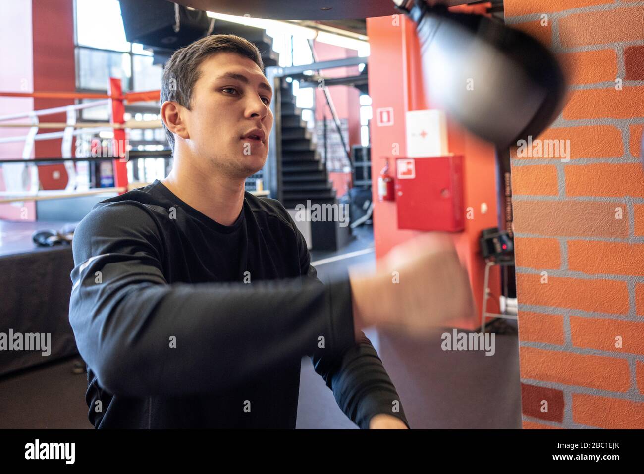 Junger Mann, der im Boxclub bei der Schlagsackübung trainiert Stockfoto