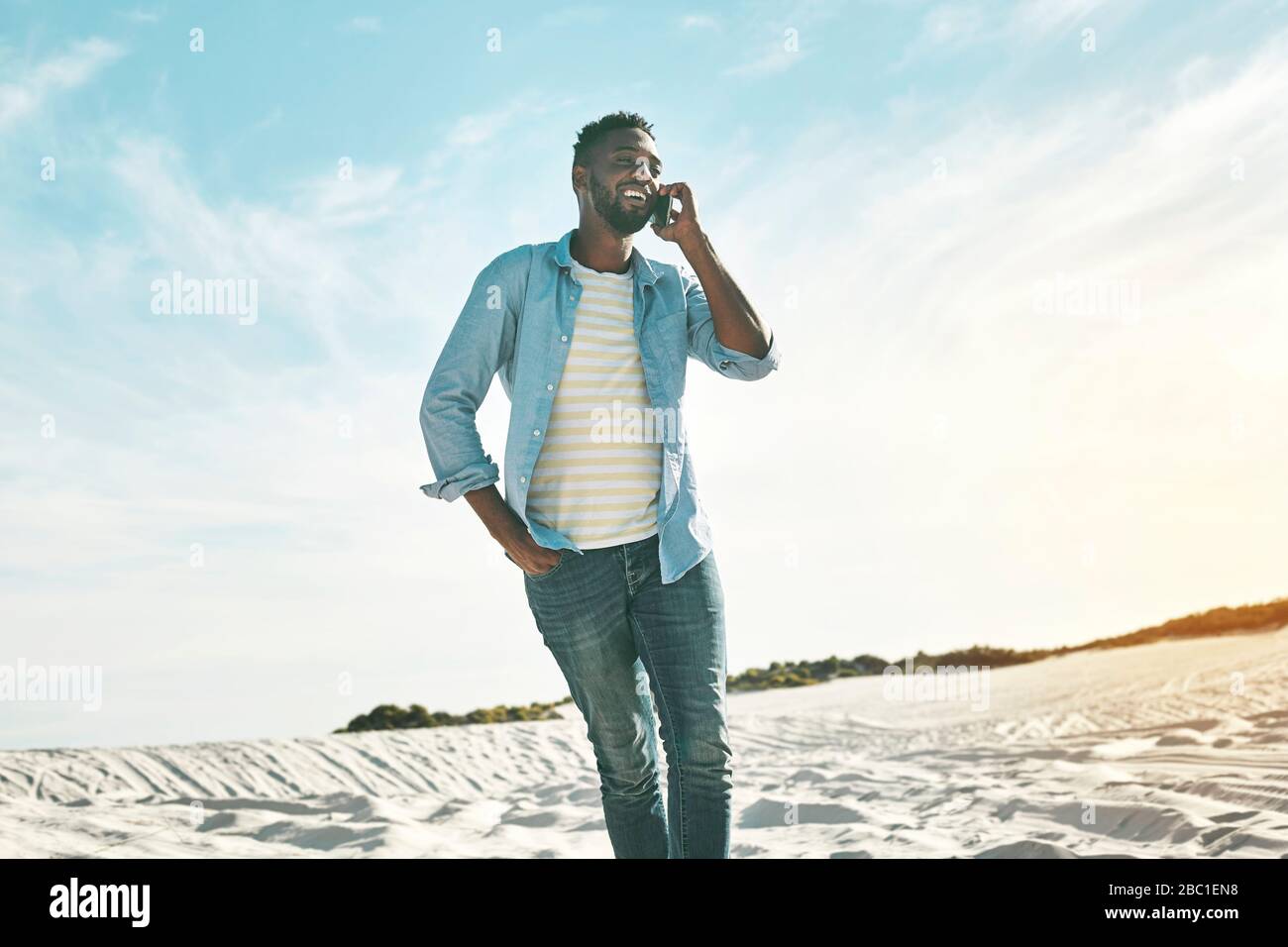 Junger Mann am sonnigen Strand telefoniert Stockfoto