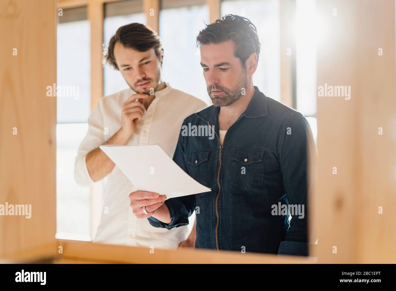 Zwei Geschäftsleute mit Dokument in einem offenen Holzbüro Stockfoto