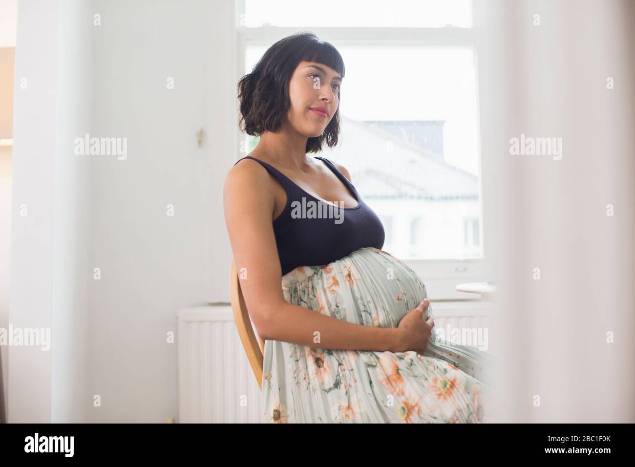 Nachdenkliche schwangere Frau, die Magen hält Stockfoto