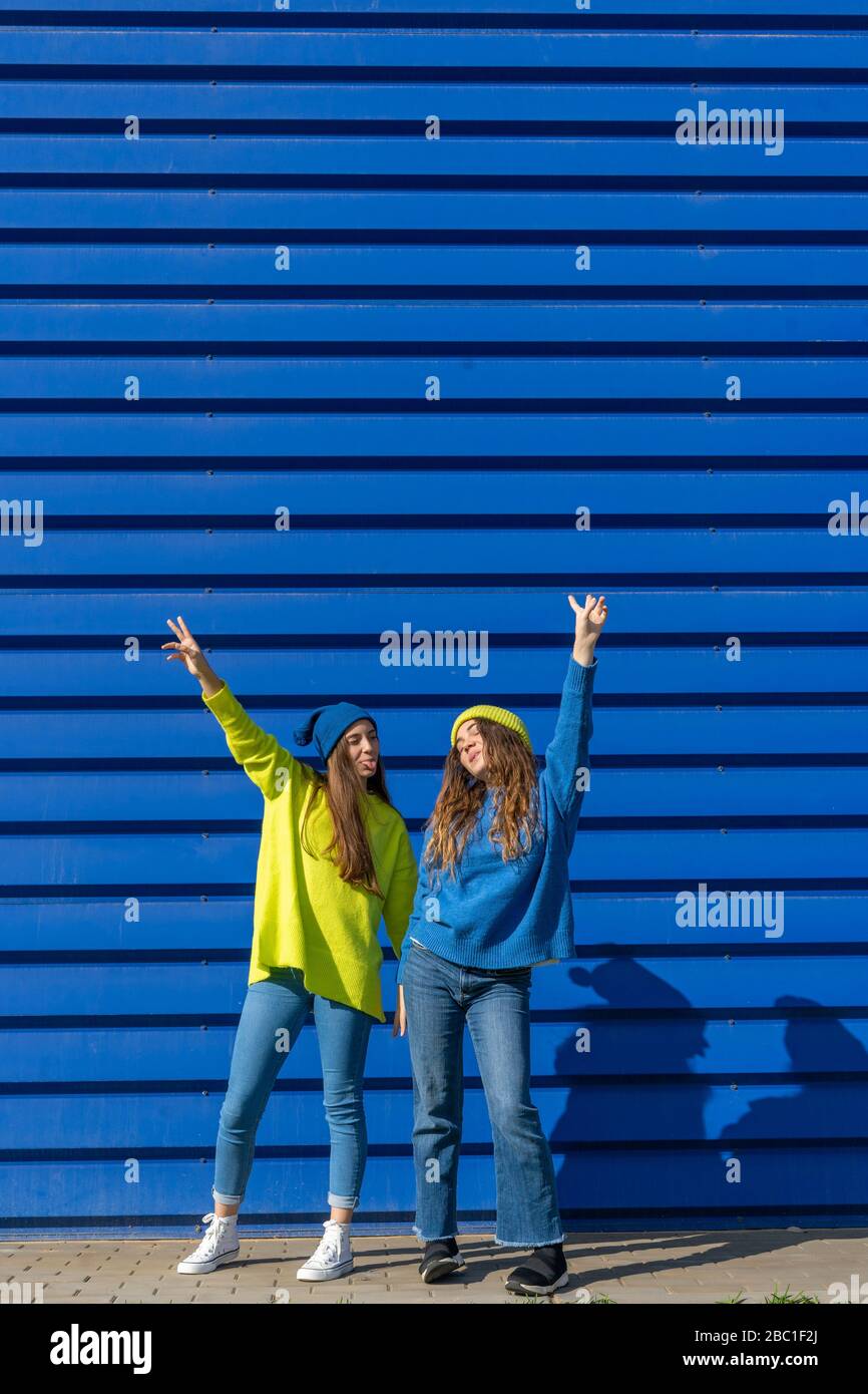 Zwei Teenager-Mädchen tragen passende Kleidung vor blauem Hintergrund Stockfoto