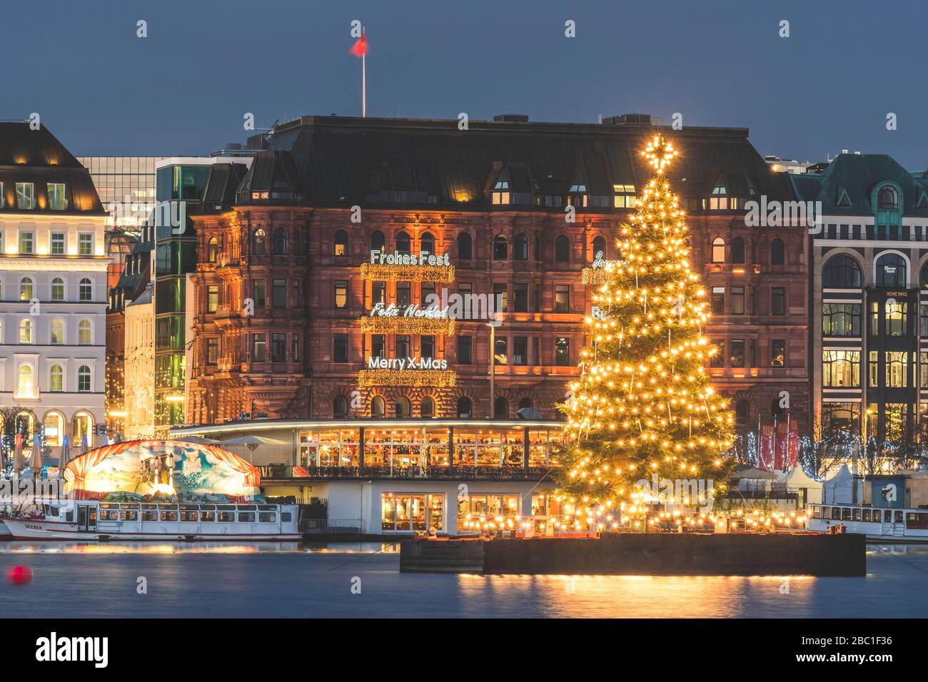 Deutschland, Hamburg, beleuchteter Alstertanne Baum in der Dämmerung mit Jungfernstieg Promenade im Hintergrund Stockfoto