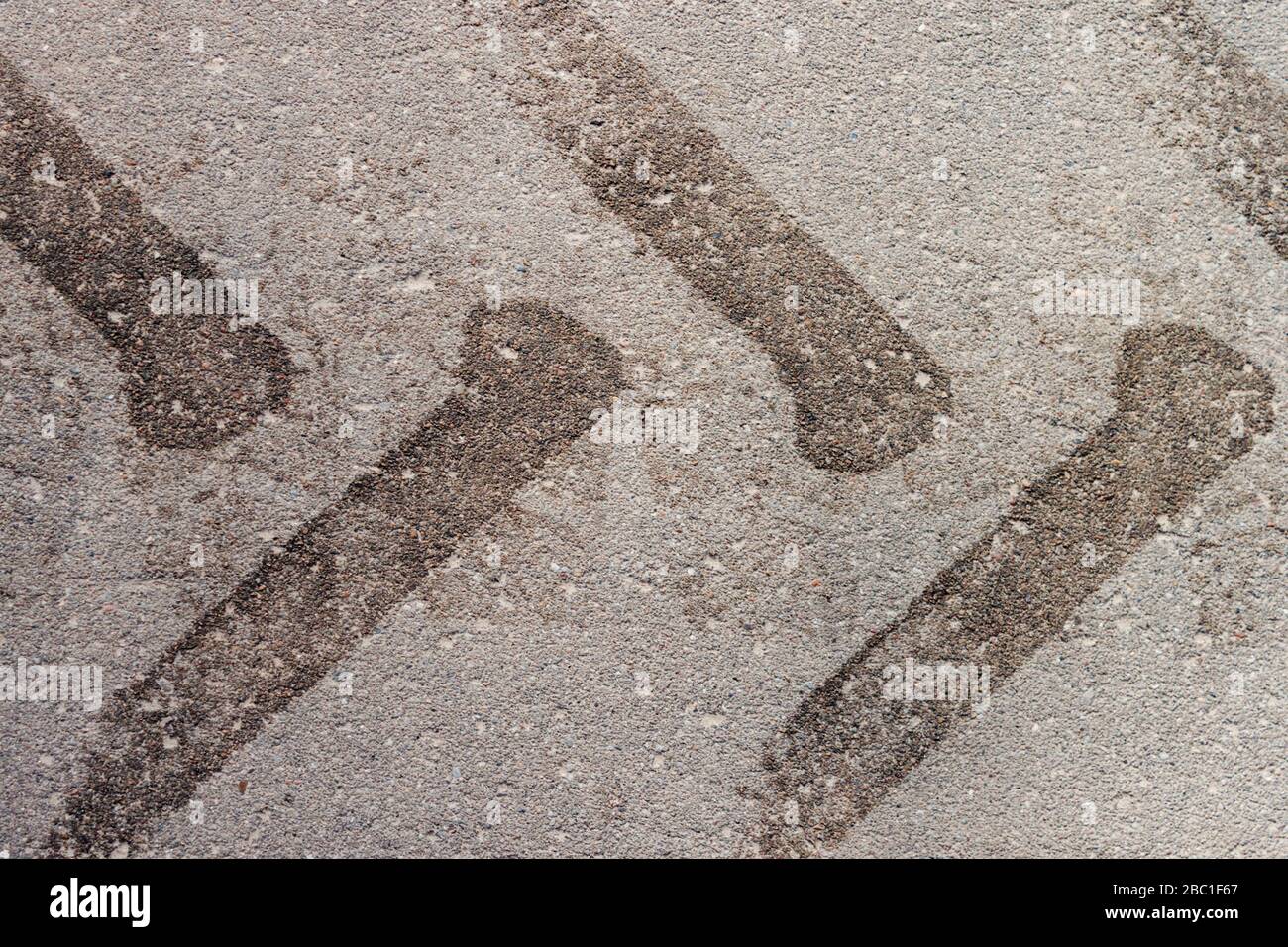 LKW- oder Traktorreifen drucken Spuren auf grauer Asphaltstraße in der Nähe Stockfoto