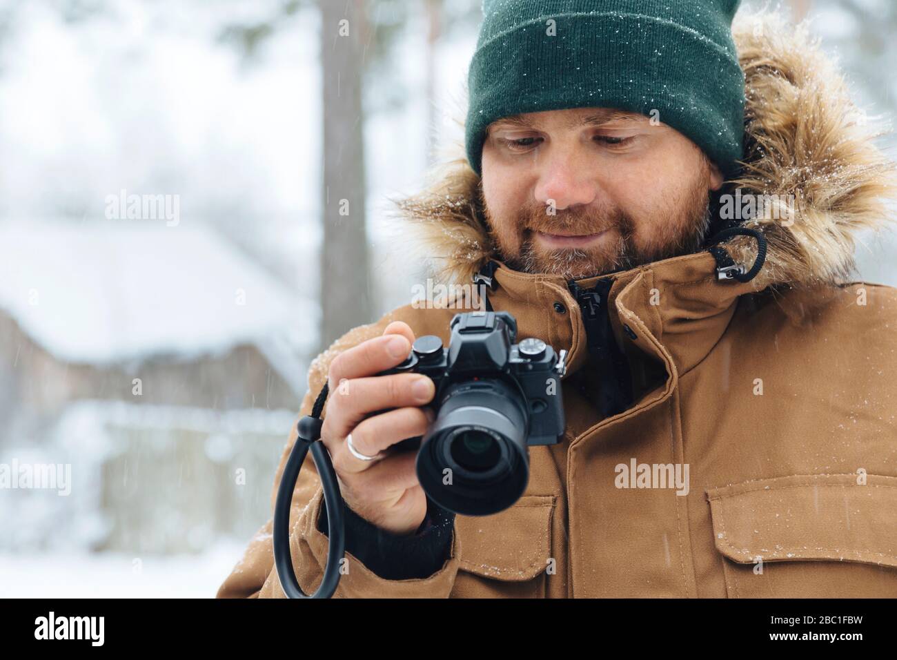 Porträt des lächelnden Mannes, der im Winter auf die Digitalkamera schaut Stockfoto