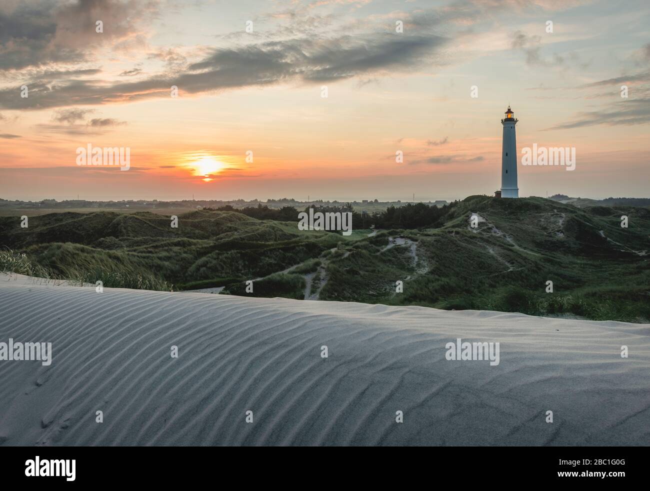 Dänemark, Hvide Sande, gewellte Sanddüne bei Sonnenuntergang mit Leuchtturm im Hintergrund Stockfoto