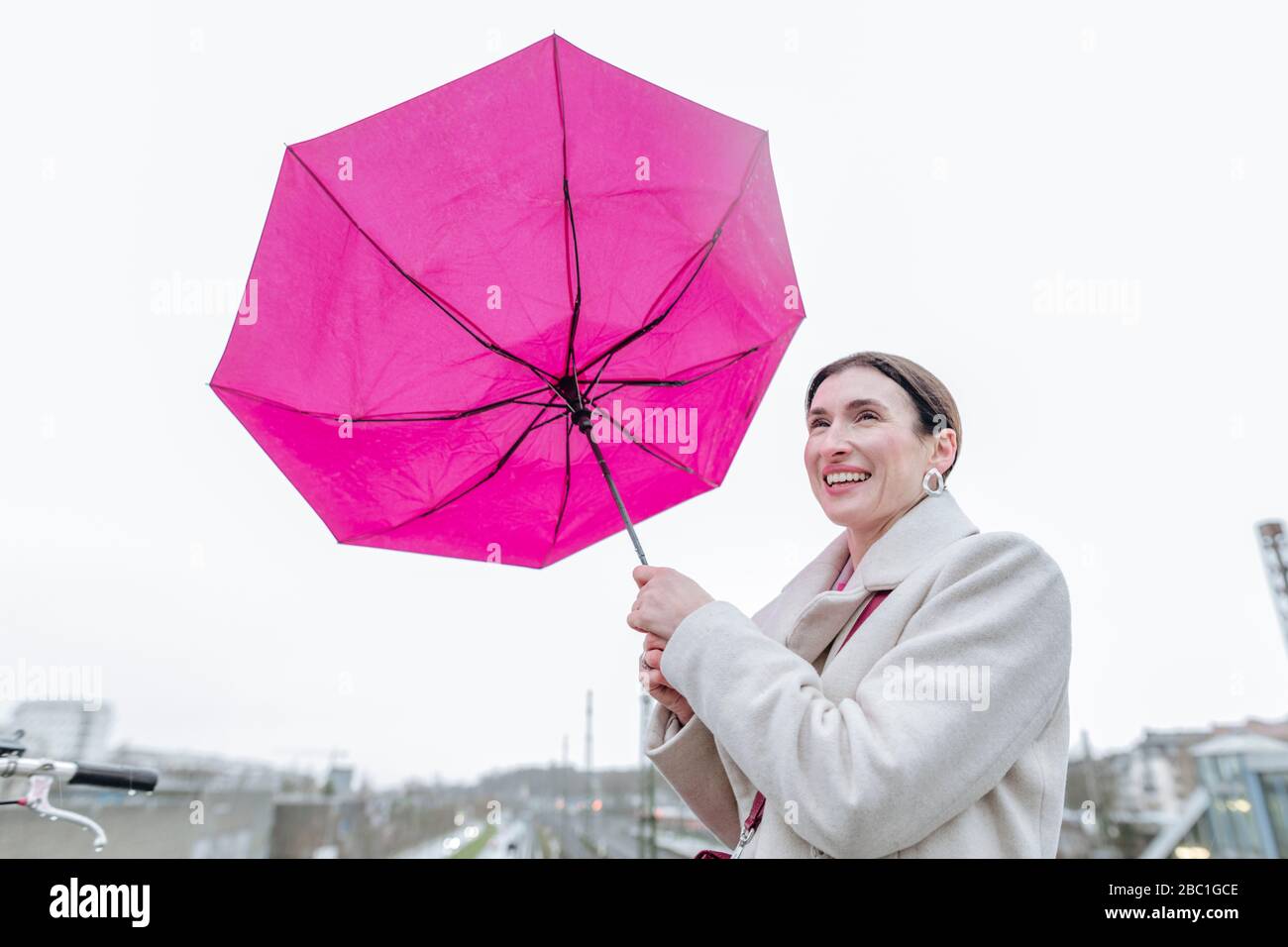 Lächelnde Frau mit rosa Regenschirm Stockfoto