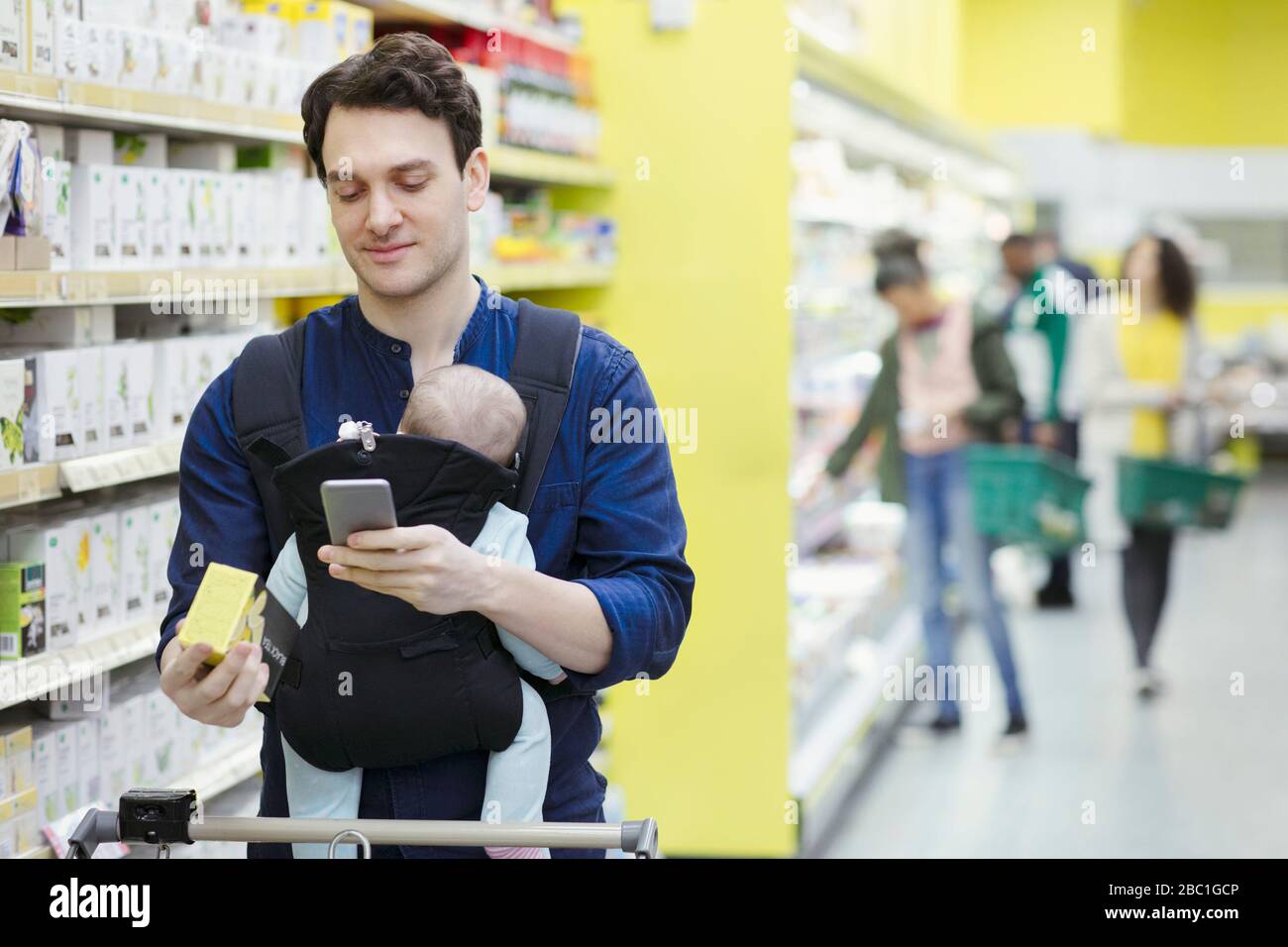 Vater mit Babyetikett auf dem Karton im Supermarkt Stockfoto