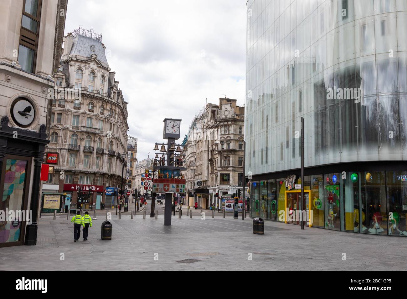 Ein menschenleerer Leicester Square im Zentrum Londons während des Ausbruchs des Corona-Virus. Zwei einsame Polizisten sind zu sehen. Stockfoto