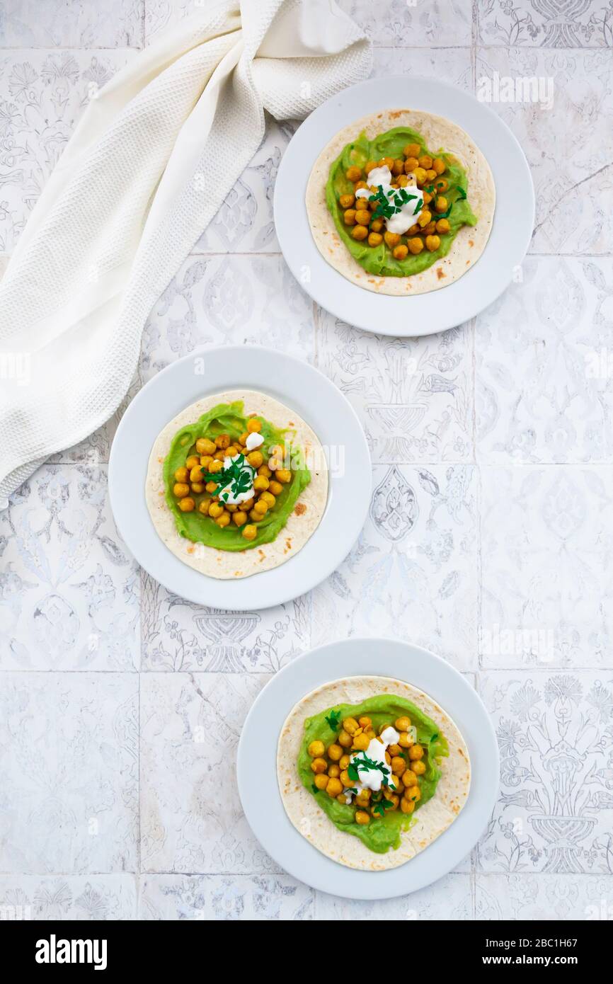 Pita-Brotteller mit Avocados, Kurkuma-Kichererbsen, Joghurt und Petersilie Stockfoto