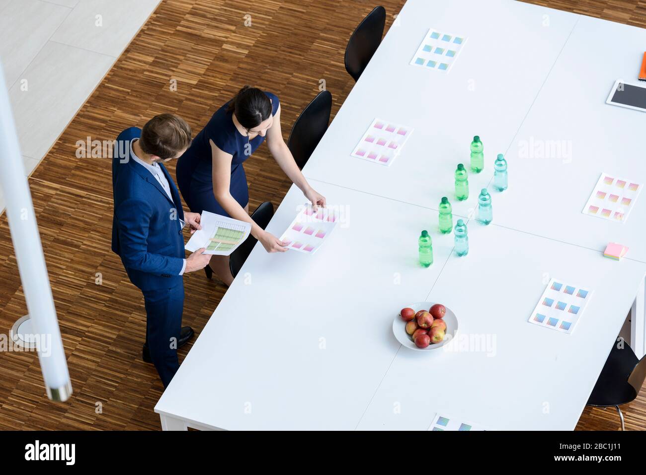 Geschäftsmann und Frau bereiten Sitzungssaal für eine Sitzung vor, erhöhte Aussicht Stockfoto