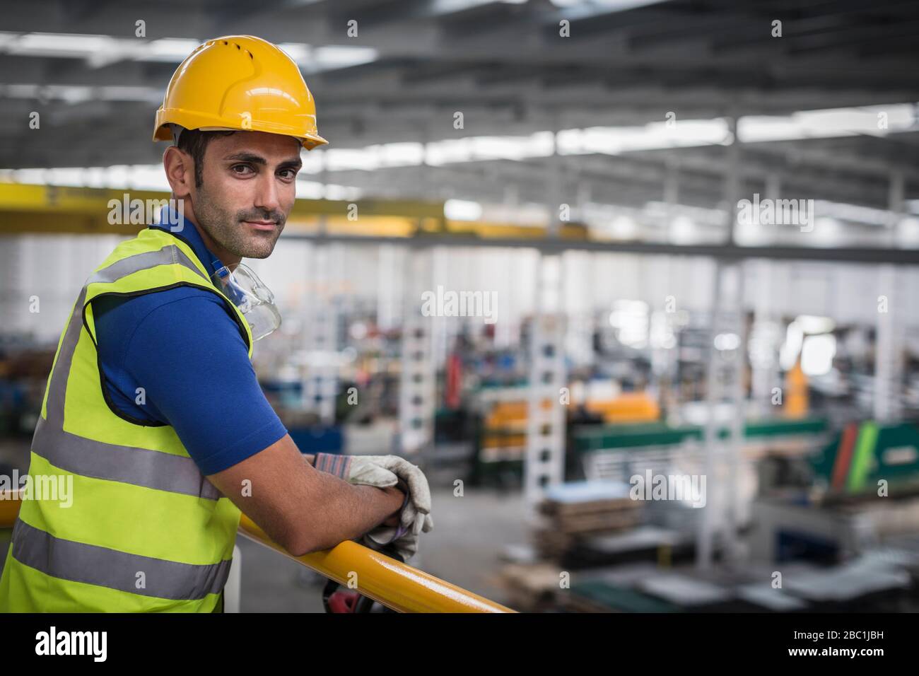 Portrait selbstbewusster männlicher Vorgesetzter, der sich werkseitig auf das Bahnsteiggeländer neigt Stockfoto